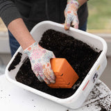 Person planting seeds in a container with gardening gloves on 5x5 Deep Grow Tray Inserts