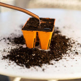 Orange seedling tray with soil being filled in a close-up shot.