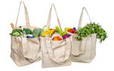 Three beige tote bags filled with groceries on a white background