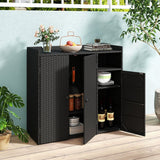 A black wicker-textured outdoor storage cabinet with two doors, one open to show shelves and stored dishes and wine bottles, placed on a light wood deck against a pale blue wall with potted plants around it.