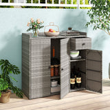 Gray wicker-style sideboard cabinet with two doors open, styled on a patio with flowers, books, dishes, and wine bottles inside and around it.