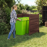 Woman interacting with green trash bins under a wooden cover in a garden setting