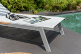 White lounge chair with a magazine and sunglasses by a poolside