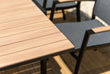 Wooden outdoor table with black metal chairs on a patio