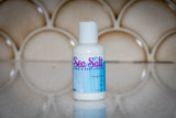 Bottle of 'Sea Salt' hand and body lotion on a reflective surface with a tiled background