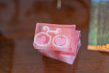 Pink soap with bicycle and heart design on a wooden surface