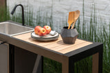 Outdoor kitchen setup with sink, cutting board, apples, and utensils.