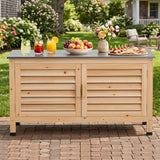 A light natural wood outdoor Outdoor Storage Cabinet with Stainless Steel Countertop with louvered doors and a dark gray top, styled on a brick patio with drinks, fruit, flowers, and appetizers in a garden setting.