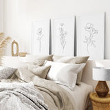 Neatly made bed with beige and white bedding, decorative pillows, and wall art in a bedroom setting.