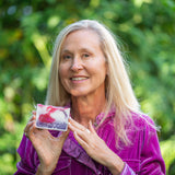 Woman holding a POMEGRANATE GOAT'S MILK SOAP SLICE 5 oz. against a green outdoor background