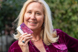 Woman holding a POMEGRANATE GOAT'S MILK SOAP SLICE 5 oz. with a blurred green background
