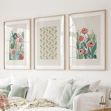 Botanical Pink Poppies Wall Art Poster Decor in wooden frames on a wall above a white sofa.