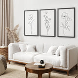 Modern living room with a white sofa, wooden coffee table, and floral wall art.