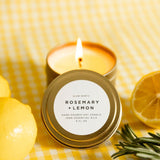 Rosemary and Lemon candle with a lit wick on a yellow checkered background