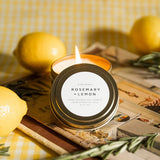 Candle labeled 'Rosemary + Lemon' with lemons and a checkered cloth in the background