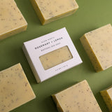 Box of Slow North Rosemary + Lemon natural bar soap surrounded by unboxed soap bars on a green background