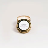 Small candle in a tin with 'Rosemary & Lemon' label on a light background