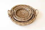 A set of nested round woven baskets with side handles, made from natural wicker or rattan, photographed on a clean white background.