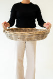 Person holding a woven basket against a plain background