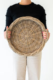 Person holding a large woven basket against a white background
