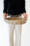 Person holding a woven basket against a plain background