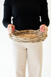Person holding a wicker basket against a white background