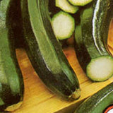 Zucchinis on a wooden cutting board with one sliced open SQUASH Seeds, Black Beauty
