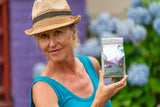 Woman holding SEA SALT & ARNICA BATH SALTS 16 oz. OR 32 oz. NEW with flowers in the background