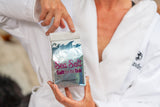 Person holding a packet of 'Sea Salt for the Tub' in a white robe.