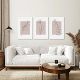 Modern living room with a white sofa, wooden coffee table, and Blush Pink Botanical Line Art Print Set of 3