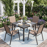 A 5-piece outdoor dining set featuring a square dark gray table and four matching armchairs with beige cushions, arranged on a light blue patterned rug in a garden patio setting.