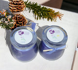 Two lavender-scented candles with decorative elements on a white surface.