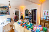 Room with a table full of colorful boxes, people in the background, and decorative elements.