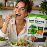 Woman eating sprouts and holding a package of Zest Greens mixed sprouting seeds in a kitchen.