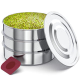 A stainless steel seed starter tray with three stacked tiers filled with green sprouts, shown with its lid propped open and a small red square insert on a white background.