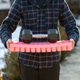 Person holding Air Prune Propagation Tray - 72 Cell with two dumbbells on top, outdoors.