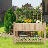 Wooden raised garden bed with plants and gardening tools on a sunny day.