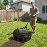 Person using a 24 Inch Compost Spreader Peat Moss Spreader Roller with Height-Adjustable T-Shaped Handle-Black on a grassy area in front of a house