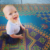Baby sitting on a colorful Turkish Aqua patterned rug