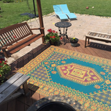 Colorful patterned Turkish Aqua rug on a wooden deck with outdoor furniture and plants.