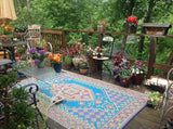 Outdoor deck with a colorful Turkish Aqua rug, chairs, and potted plants on a wooden deck.
