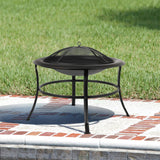 Black metal fire pit on a patio with grass in the background