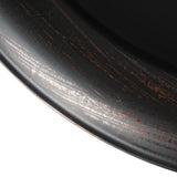 Close-up of a black ceramic plate with a textured surface on a white background