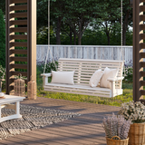 Traditional Porch Swing with cushions on a wooden deck with plants and a fence in the background