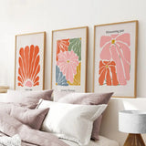 Henri Matisse Flower Market Colorful Poster on a wall above a bed with pillows and a lamp.