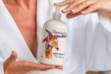 Person holding a bottle of The Appalachian Goat's Milk Lotion with colorful label.