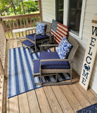 Outdoor patio with chairs, cushions, and a striped rug on a wooden deck.