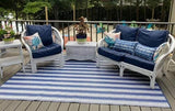 Outdoor patio set with white furniture and blue cushions on a striped rug.