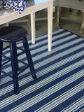 Blue and white striped rug on a wooden floor with a blue stool.