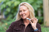 Woman holding VANILLA SWIRL LUXURY LIP BUTTER™ - THE APPALACHIAN GOAT outdoors with greenery in the background